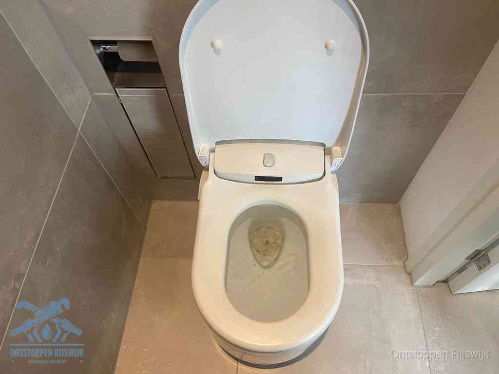 Een wit hangtoilet waarin een prop wc-papier op het water blijft drijven, een duidelijk signaal van een verstopte wc in Rijswijk