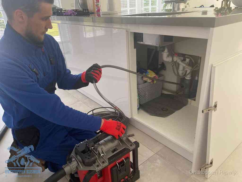 Een monteur reinigt de keukenafvoer grondig met een veermachine om terugkerende gootsteenverstoppingen te voorkomen in Rijswijk