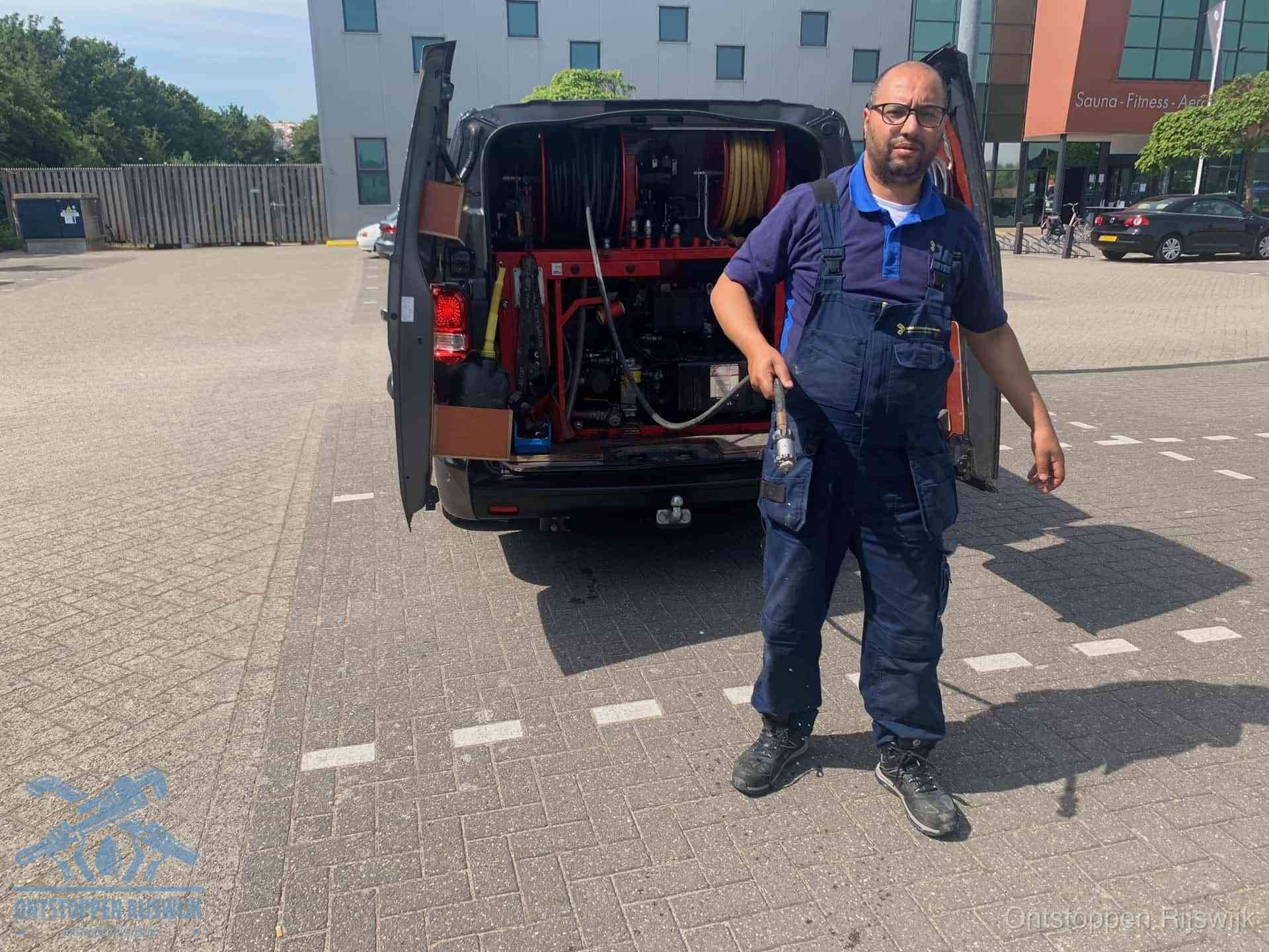 Een monteur bij zijn bestelbus met een hogedruk- en rioolreinigingsunit, klaar om de oorzaak van terugkerende wc-verstoppingen aan te pakken in Rijswijk