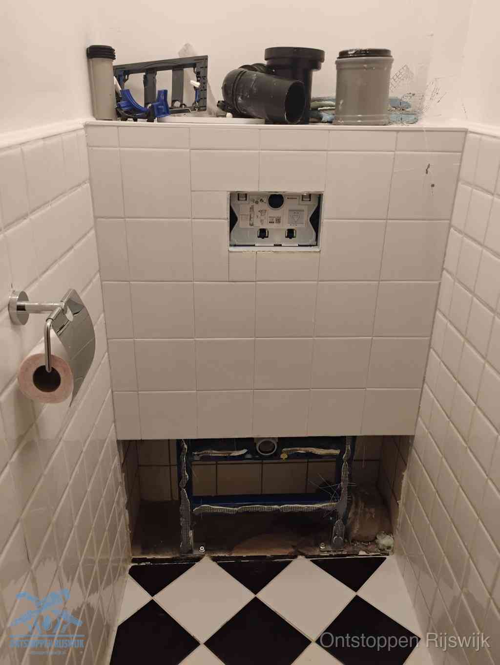 Een toiletruimte waar het hangtoilet en de inbouwreservoir-onderdelen zijn vrijgelegd voor onderhoud, periodiek nazicht voorkomt een wc-verstopping in Rijswijk