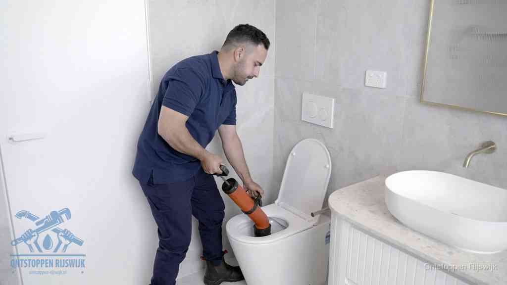 Een monteur gebruikt een handmatige perspomp (toiletontstopper) op een wandcloset tijdens het professioneel wc ontstoppen in Rijswijk