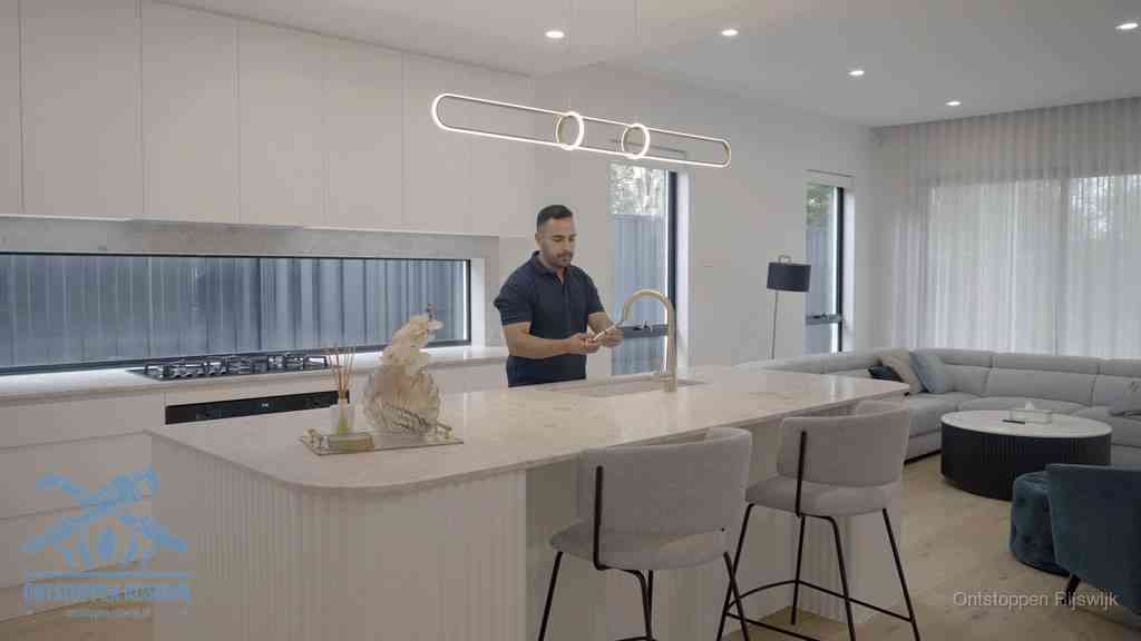 Een bewoner bij de keukenspoelbak die zelf aan de slag gaat met een verstopte gootsteen in Rijswijk